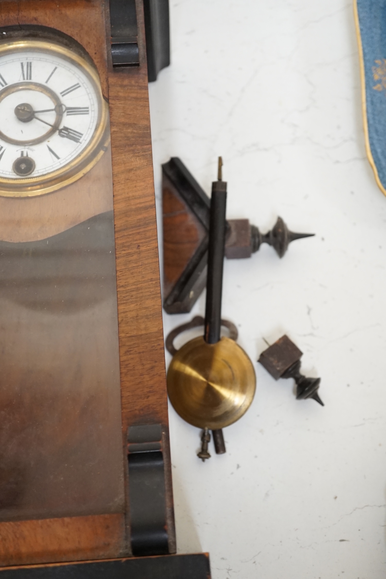 A small walnut cased wall clock with enamel dial with pendulum and key. Condition - poor